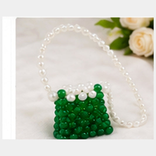 Green and white mini beaded purse displayed in a premium neutral floral lifestyle setting