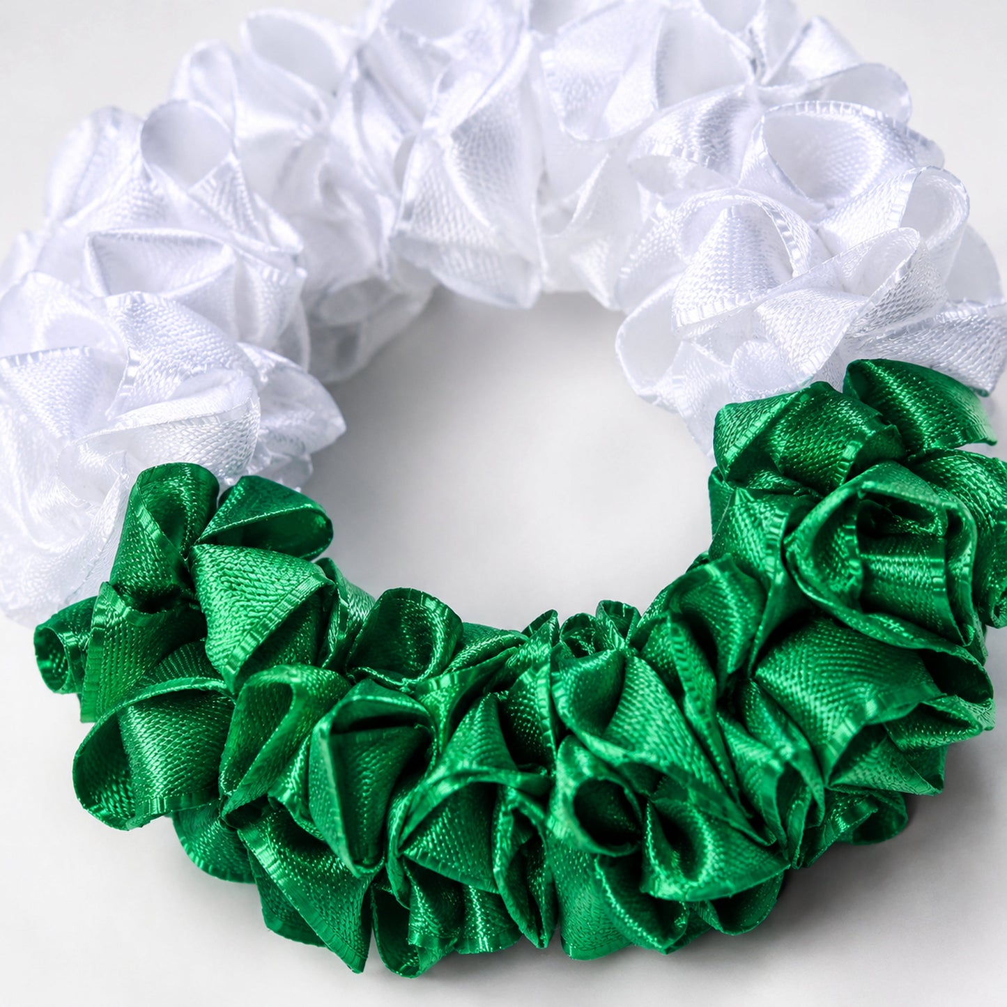 Macro close-up of the green and white satin ribbon folds and floral craftsmanship on the Azadi gajra