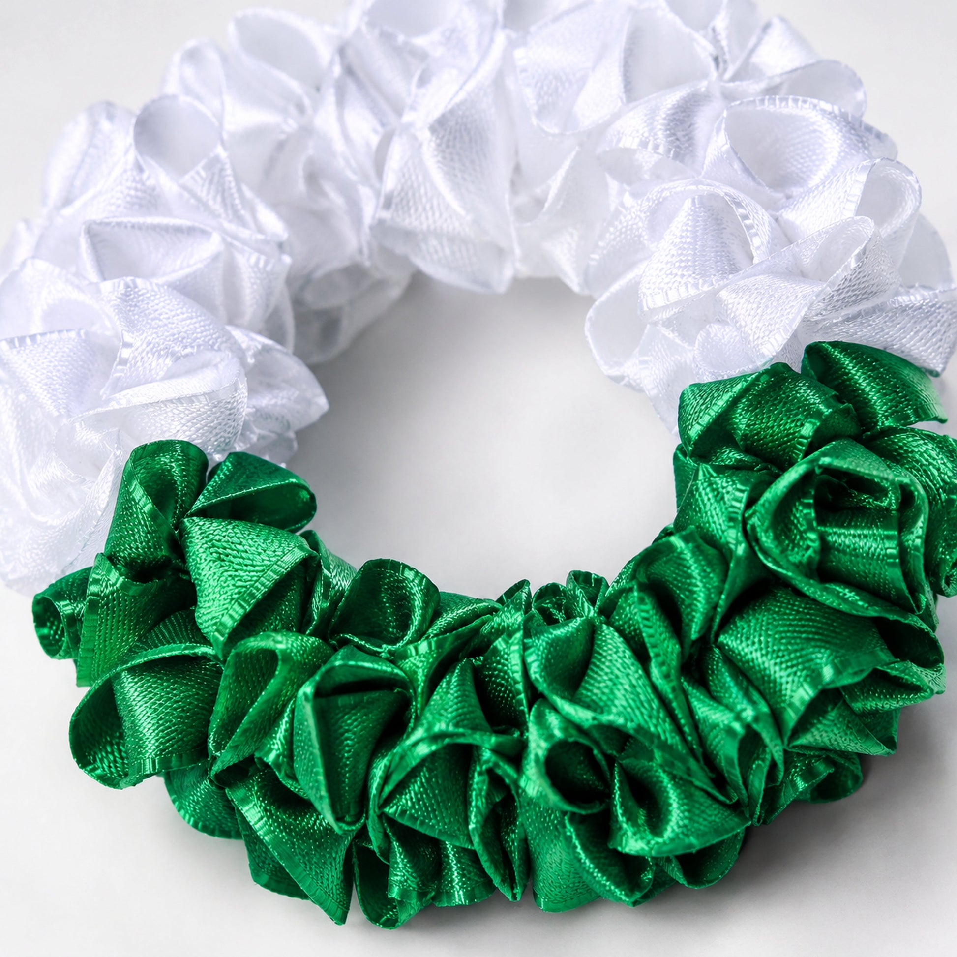 Macro close-up of the green and white satin ribbon folds and floral craftsmanship on the Azadi gajra