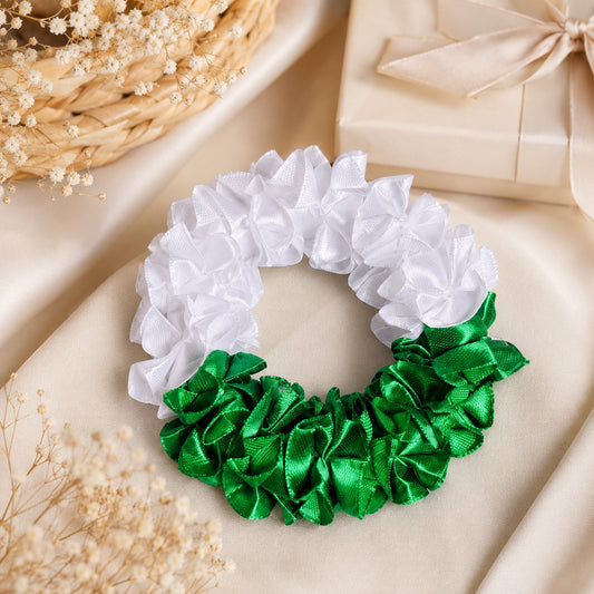 Green and white floral gajra styled on a premium neutral gift setting