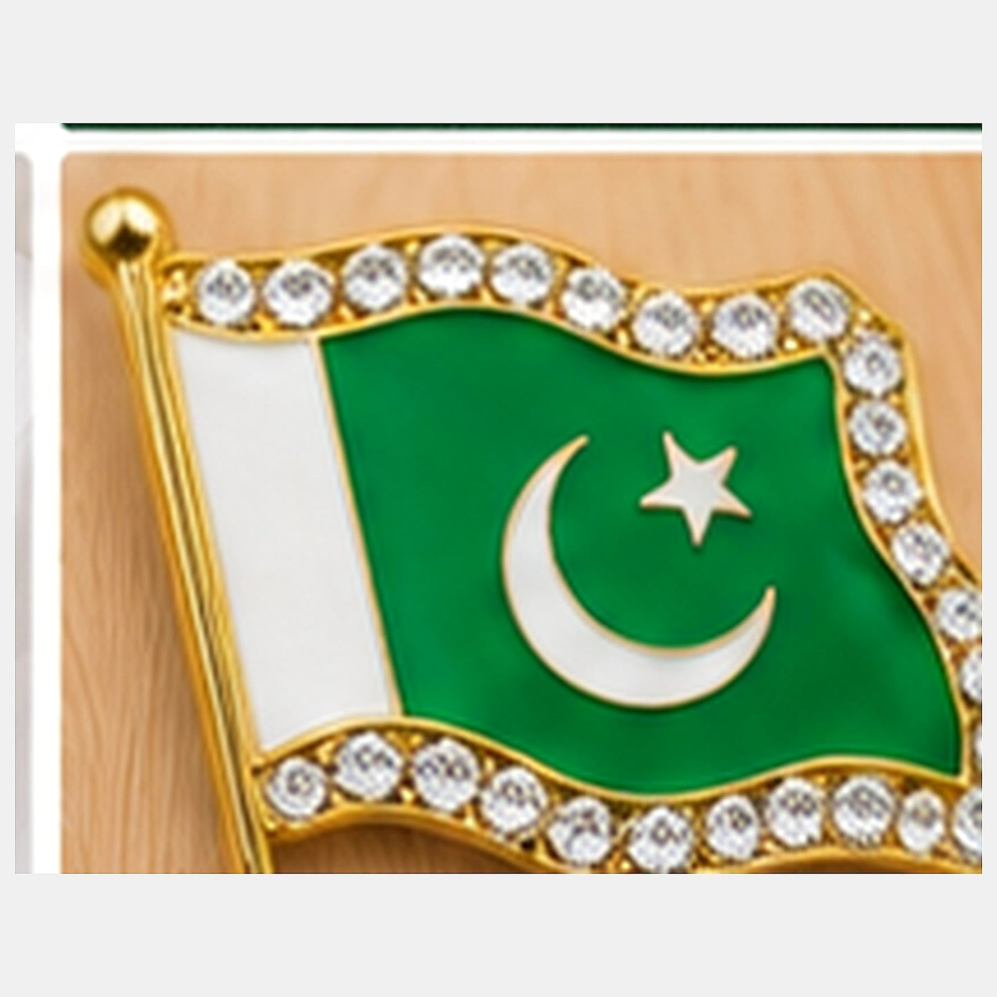 Macro close-up of one Pakistan flag metal badge showing enamel, crescent, star, gold-tone border and clear stones