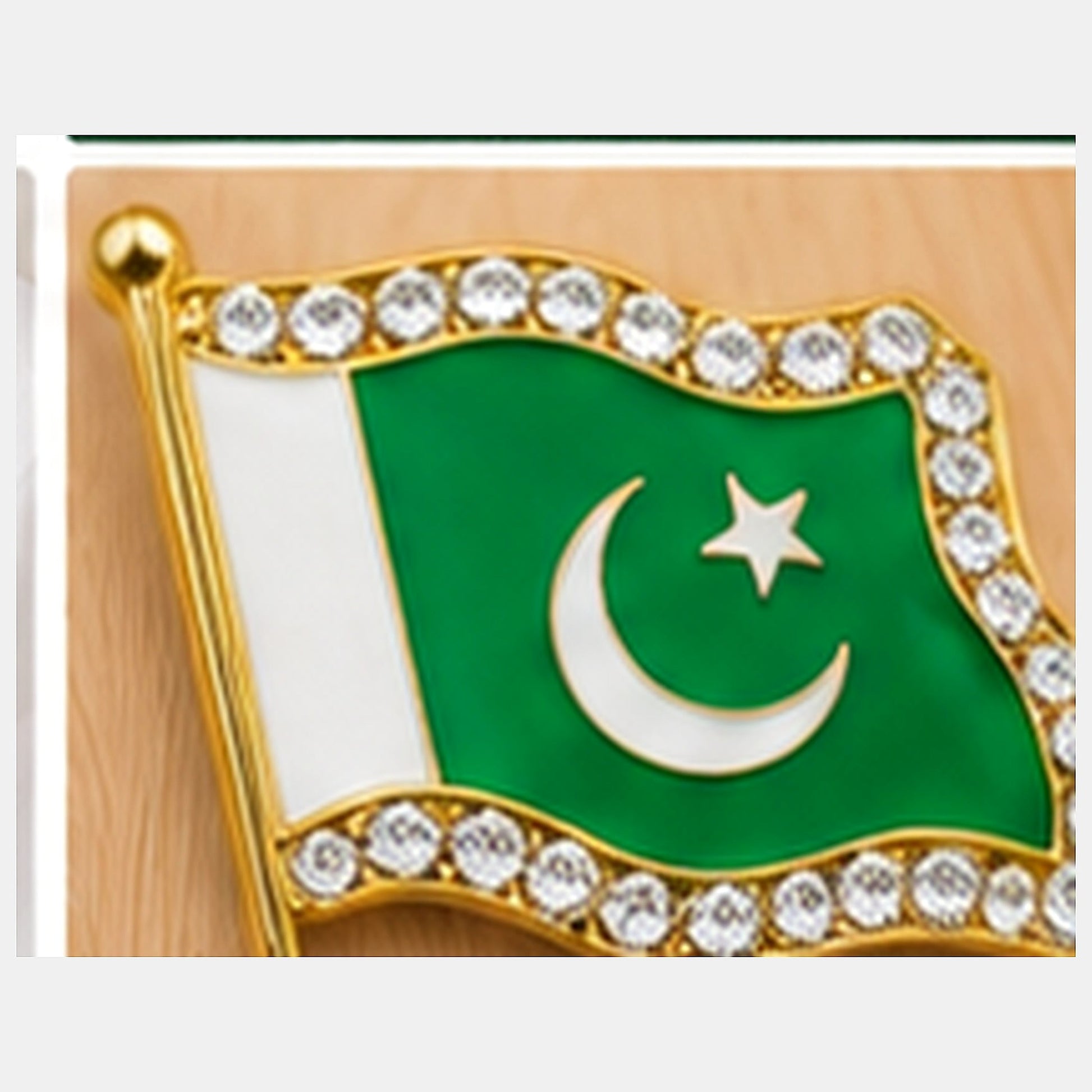 Macro close-up of one Pakistan flag metal badge showing enamel, crescent, star, gold-tone border and clear stones