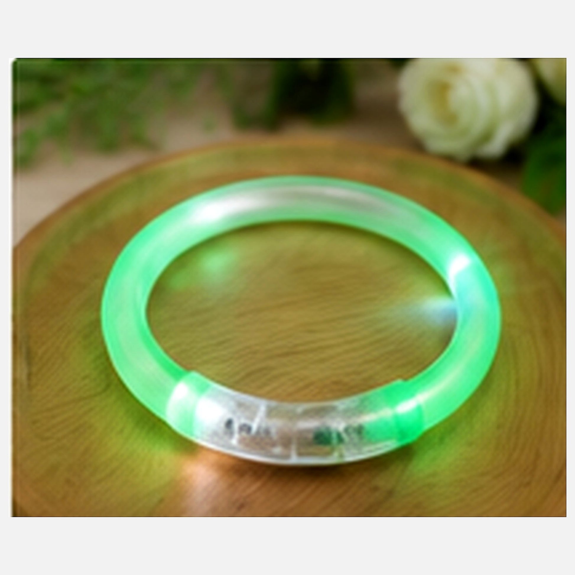 Green LED glow bracelet displayed on a premium wooden tray in an evening lifestyle setting