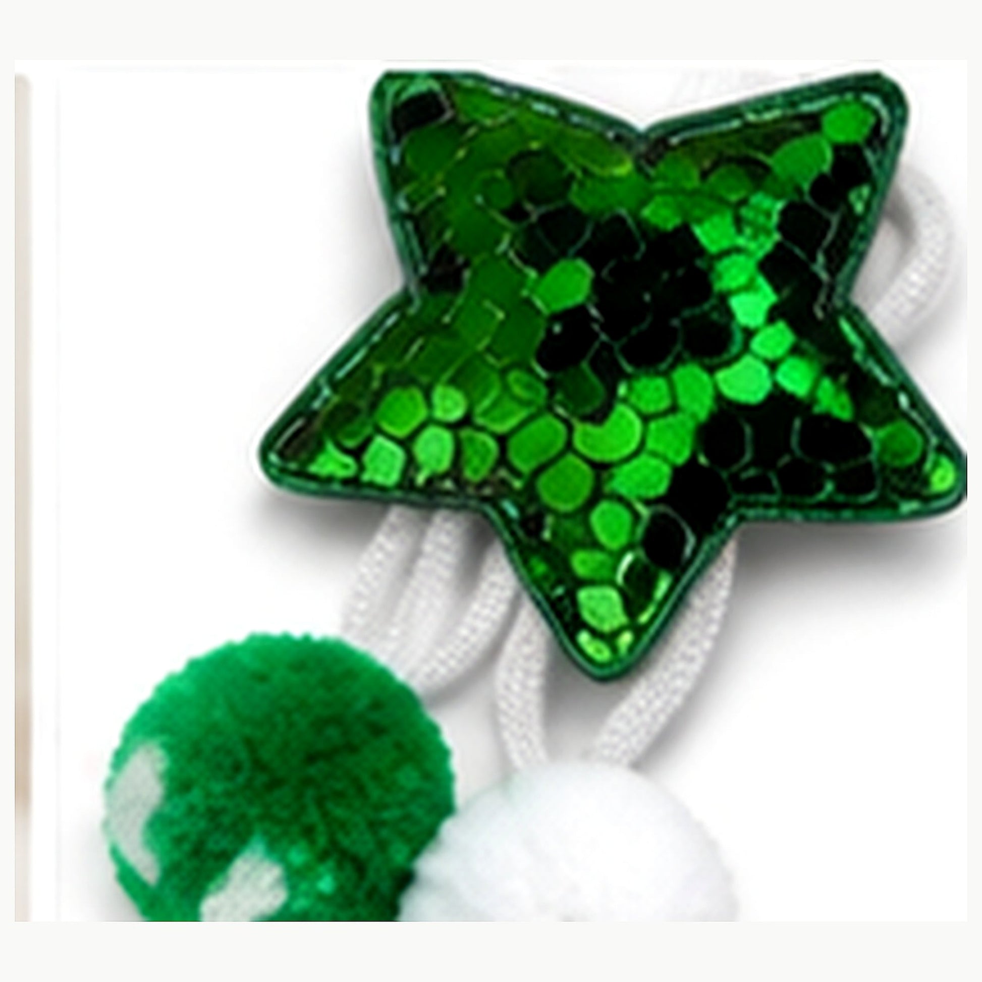 Macro close-up of green sequins, white elastic, cords and two green-and-white pom-poms